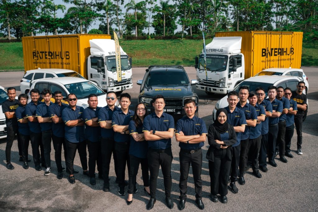 The Baterihub team posing confidently with their branded fleet of trucks and vehicles, showcasing unity and commitment.