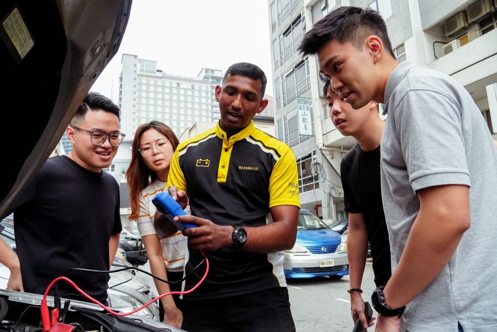 Baterihub technician demonstrating a battery test to a group of customers