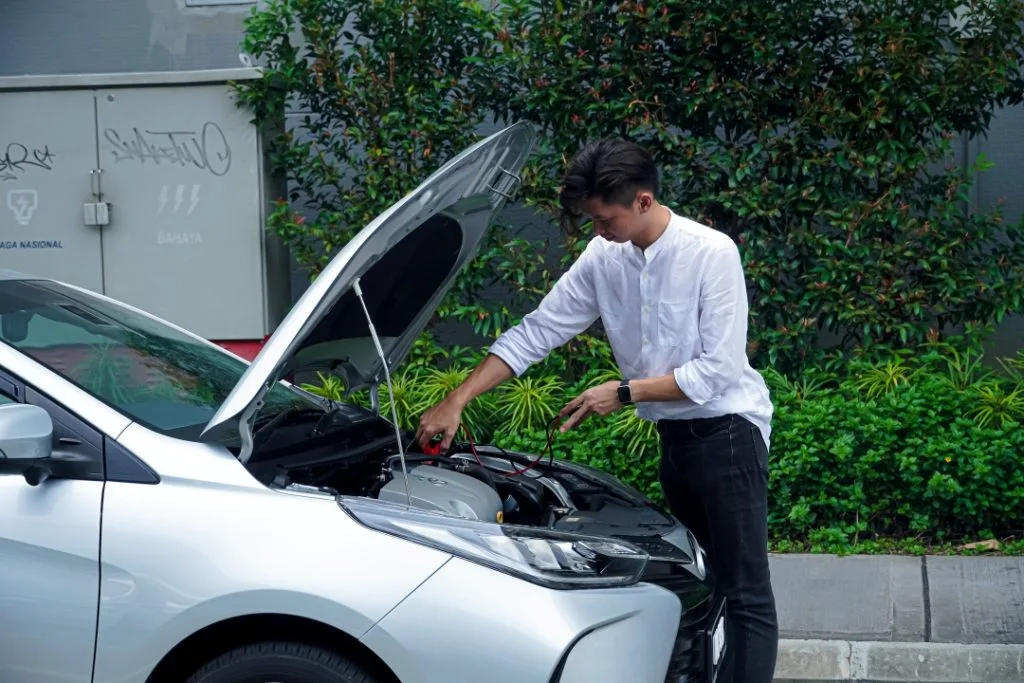 A Boy trying to change his car battery himself.