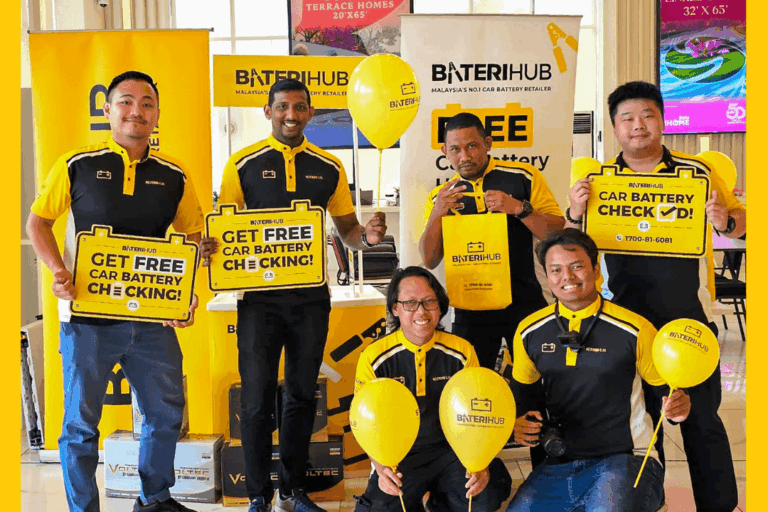 Alam Sari Blog Cover BateriHub team promoting free car battery health check event with branded signage and balloons at indoor corporate event in Malaysia.